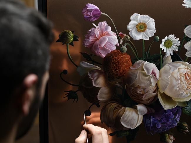 Artist Sebastian Galloway adds the finer details to his floral paintings on copper which form part of his latest exhibition Suspended in Bloom. Picture: Supplied