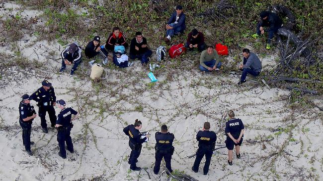 Police and Border Force officers guard nine people who were on a fishing boat that arrived off the Queensland coast on Sunday. Picture: Marc McCormack