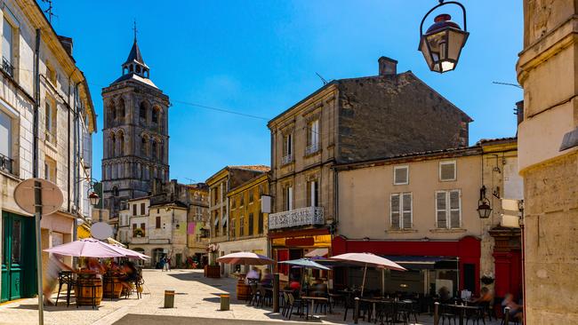 Central street of French town of Cognac overlooking bell tower of Saint Leger Church.