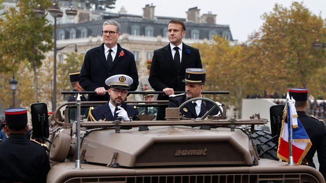 TOPSHOT - France's President Emmanuel Macron (R) and Britain's Prime Minister Keir Starmer review troops aboard a command vehicle on the Place de l'Etoile, as part of the commemorations marking the 106th anniversary of the November 11, 1918, Armistice, ending World War I (WWI), in Paris, on November 11, 2024. (Photo by Ludovic MARIN / POOL / AFP)