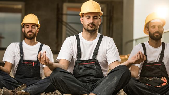 Construction workers doing yoga during a work break.