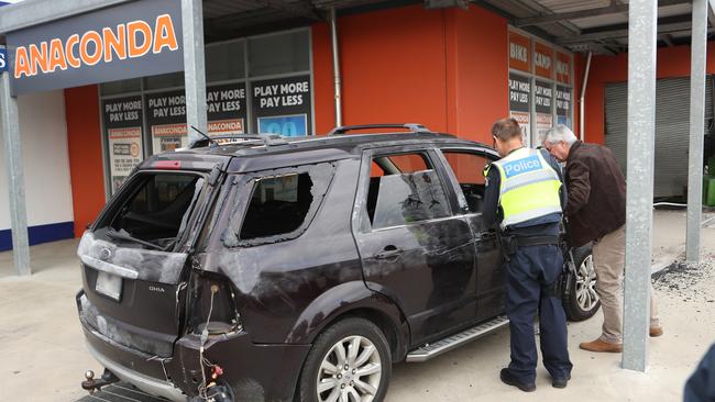 Police inspect the car outside the Frankston store. Picture: David Crosling