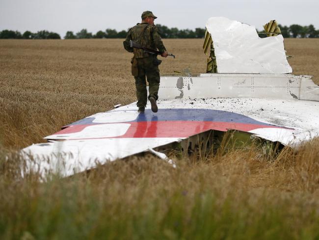 Tense situation ... an armed pro-Russian separatist stands on part of the wreckage of MH17. Picture: Maxim Zmeyev