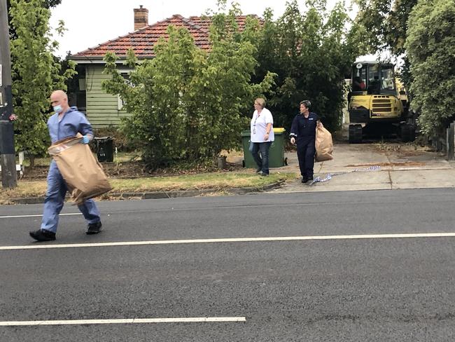 Forensic police leave a Bundoora property with large brown bags. Picture: James Mottershead