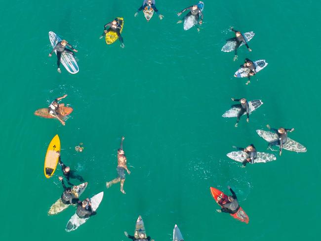 Simon Gaskill’s family and friends out on surfboards in the ocean off Skenes Creek.