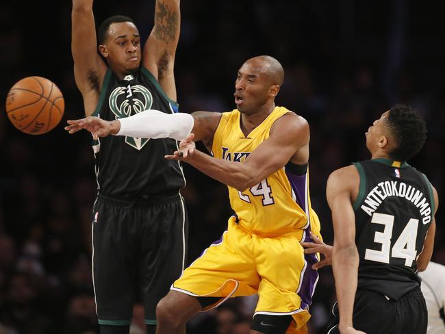 Los Angeles Laker Kobe Bryant passes off the ball between Milwaukee Bucks' John Henson, left, and Giannis Antetokounmpo.