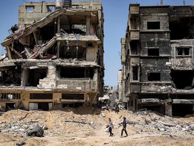 Youths walk past destroyed buildings in Khan Yunis in the southern Gaza Strip. Picture: AFP