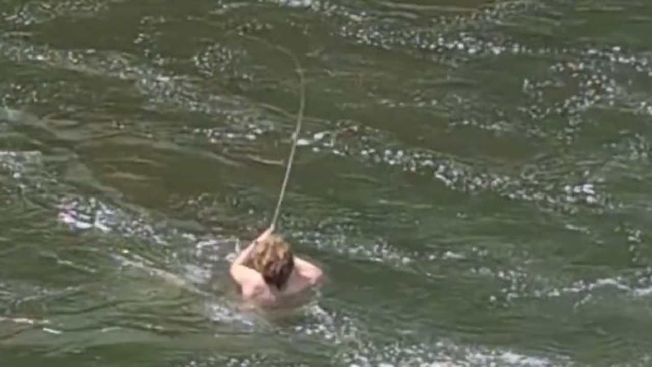 Super keen fisherman Tom Hallam swims through dicey water at Tinaroo Falls Dam spillway in an awesome display of commitment. Picture: Jess Bell