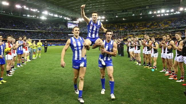 Brent Harvey is chaired off by Drew Petrie and Michael Firrito.