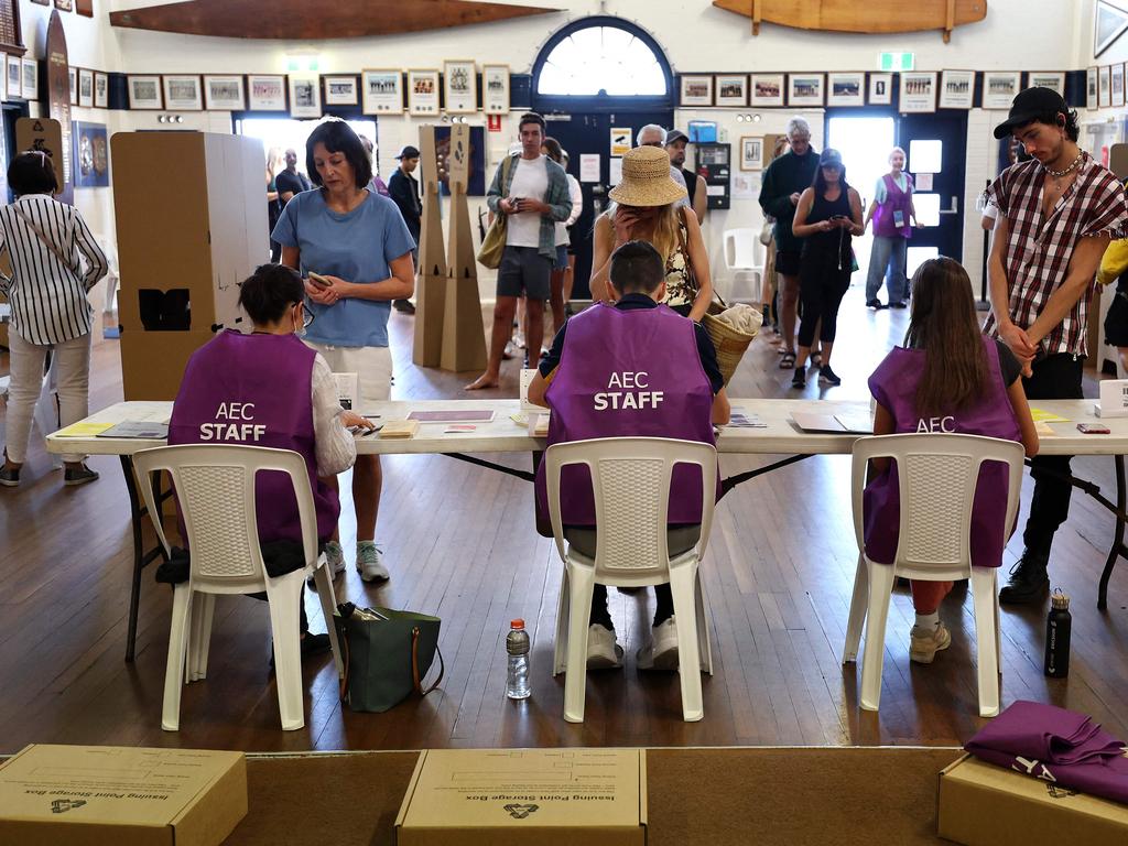 Voters collect their ballot papers from polling officers inside a polling station on Bondi Beach in Sydney. Picture: AFP