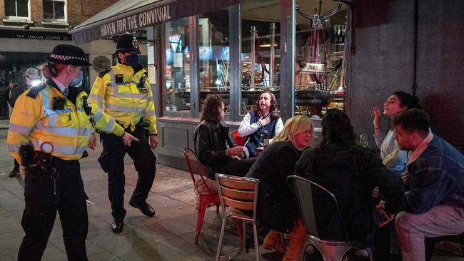 Police chat with drinkers outside a bar in Soho, in central London. Picture: Tolga Akmen / AFP