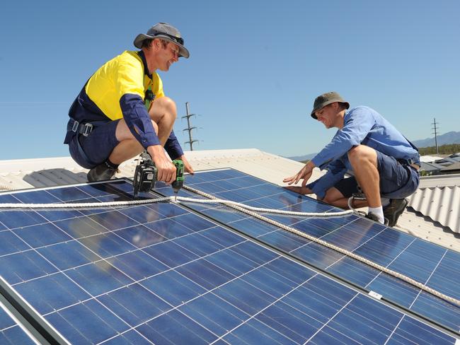 Solar Power, Electrician Adam Garrett (blue) and Robbie Mead (yellow)working on roof top solar panels.