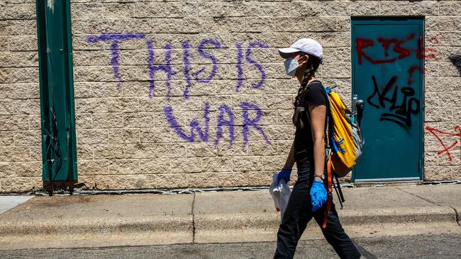 A woman walks by graffiti reading "This Is War" following a day of demonstration.