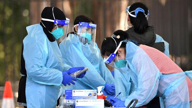 Health workers prepare to get Covid-19 test samples from the residents at a drive through testing site in Sydney. (Photo by Saeed KHAN / AFP)