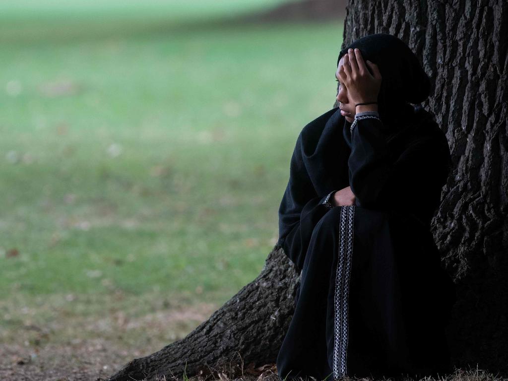 A woman sits quietly across the road from the Masjid Al Noor mosque where worshippers were massacred last Friday.