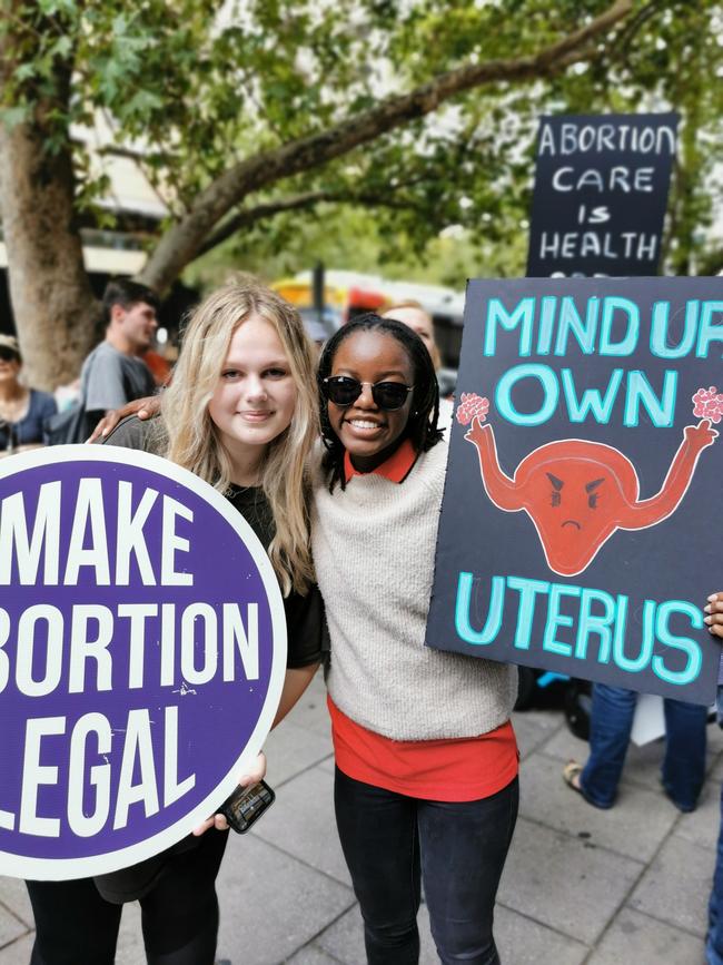 Jessica Grassen and Rutendo Maringa hold signs at the rally.