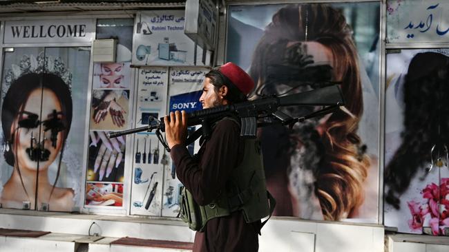 A Taliban fighter walks past a beauty salon with images of women defaced using spray paint in Shar-e-Naw in Kabul. Picture: AFP