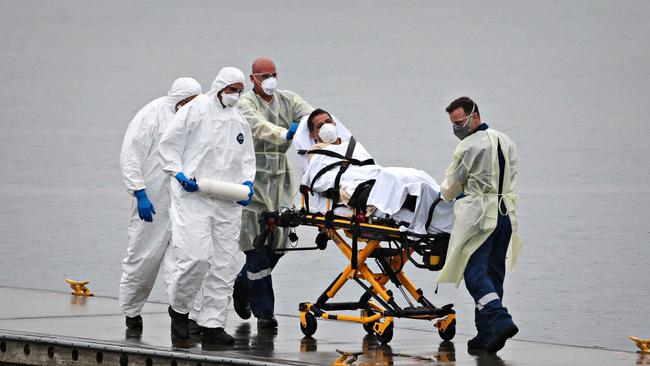 A Ruby Princess staff member being evacuated by police and medical staff to an Ambulance at Foreshore Road Boat ramp in Botany Bay, Sydney on Apri 2, 2020. Picture: Adam Yip