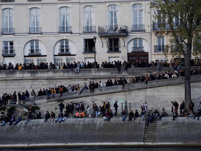 People look a fire at the landmark Notre-Dame Cathedral in central Paris from the banks of the Seine river on April 15, 2019. (Photo by Thomas SAMSON / AFP)