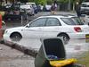 A worker (L) looks on past inundated cars on a flooded street after a storm in the eastern suburbs of Sydney on December 16, 2015. Sydney was smashed by a tornado-like storm with hail as big as golf balls and winds gusting at 200 kilometres (124 miles) an hour causing havoc with two people requiring treatment -- one for shock and one for a head wound -- in the hardest-hit suburb of Kurnell, an ambulance official said. AFP PHOTO / Peter PARKS