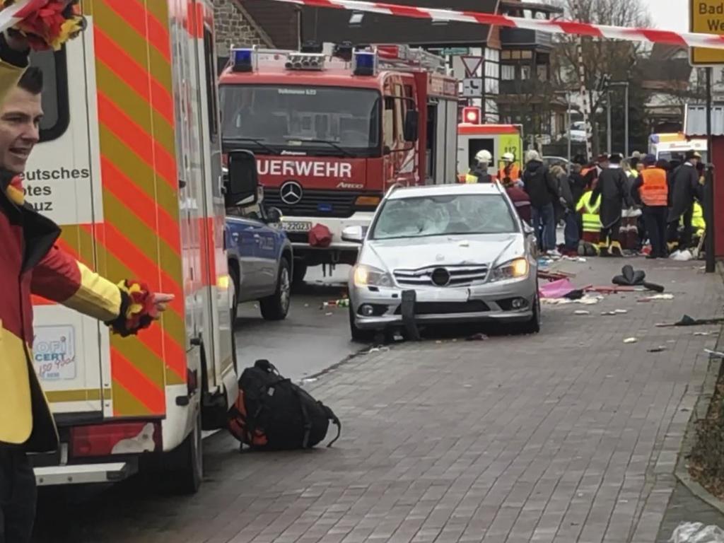 Fire brigades, rescuers and carnival revellers standing around the cordoned off site where a car drove into a procession. Picture: AFP