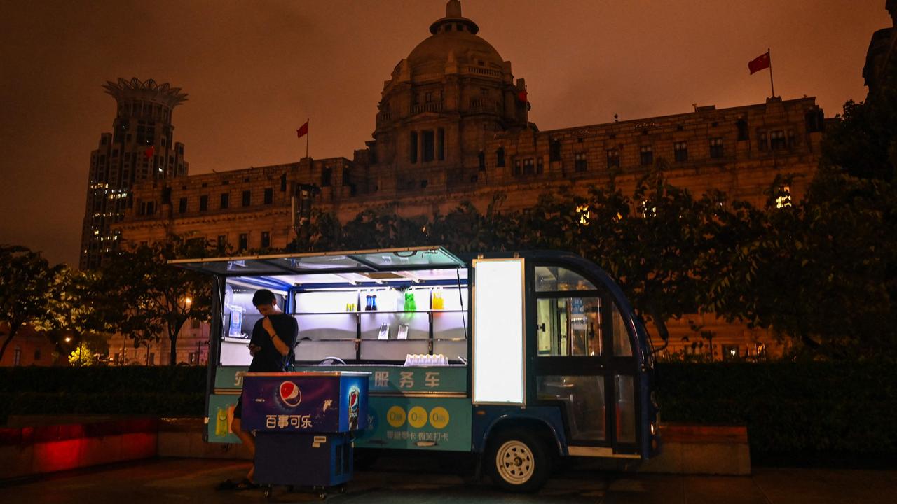 A man selling soft drinks on the Bund promenade along the Huangpu River is in darkness as decorative lights were switched off as a measure to save energy in Shanghai on August 23. Picture: Hector Retamal/AFP