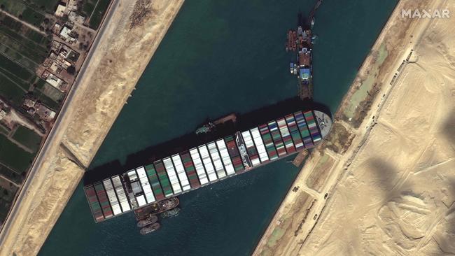 This satellite imagery released by Maxar Technologies shows tug boats and dredgers attempting to free the Taiwan-owned MV Ever Given lodged sideways and impeding all traffic through Egypt’s Suez Canal. Picture: AFP/Maxar Technologies