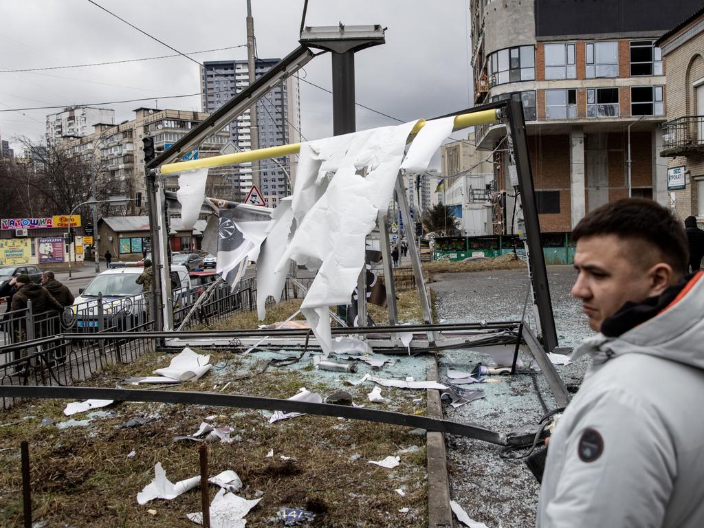 People stand around a damaged structure caused by a rocket on February 24, 2022 in Kyiv, Ukraine.