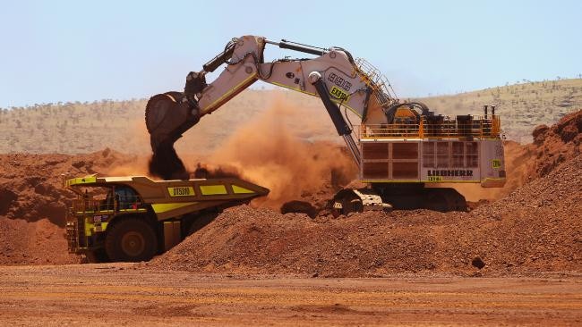 An excavator loads iron ore onto a Caterpillar truck at Fortescue’s Kings mine site. (Image: Sergio Dionisio/Bloomberg)