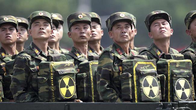 North Korean soldiers turn and look towards their leader Kim Jong Un from a military parade vehicle as they carry packs marked with the nuclear symbol. Picture: AP