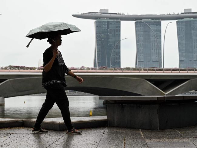 A woman walks with an umbrella at Marina Bay in Singapore on January 22, 2025. (Photo by Roslan RAHMAN / AFP)