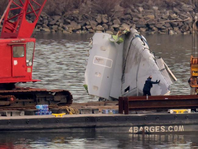 A salvage worker guides a wing of American Airlines flight 5342 as a crane lowers it onto a barge in the Potomac River. Picture: Getty Images