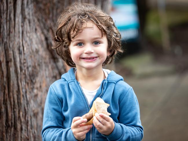 Simon Gruenaug, from Seaforth, was with his mum and dad voting at North Balgowlah Public School on Saturday and was happy to chomp into a “democracy sausage” sandwich. Picture: Julian Andrews