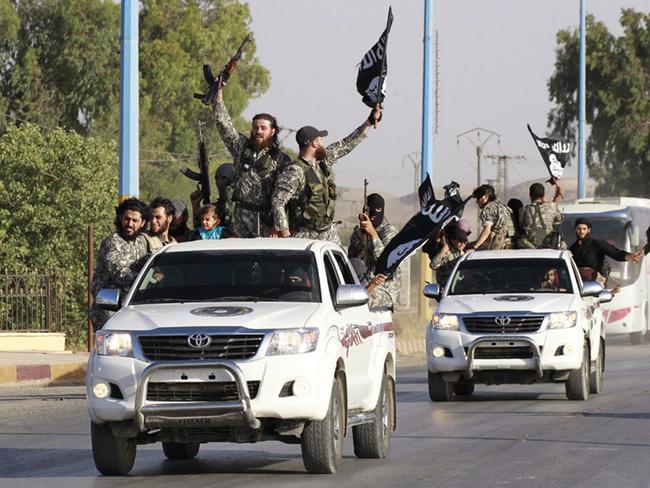 Militant Islamist fighters wave flags as they take part in a military parade along the streets of Syria's northern Raqqa province June 30, 2014. Militant Islamist fighters held a parade in Syria's northern Raqqa province to celebrate their declaration of an Islamic "caliphate" after the group captured territory in neighbouring Iraq, a monitoring service said.The Islamic State, an al Qaeda offshoot previously known as Islamic State in Iraq and the Levant (ISIL), posted pictures online on Sunday of people waving black flags from cars and holding guns in the air, the SITE monitoring service said. REUTERS/Stringer (SYRIA - Tags: POLITICS CIVIL UNREST CONFLICT TPX IMAGES OF THE DAY) - RTR3WHLH