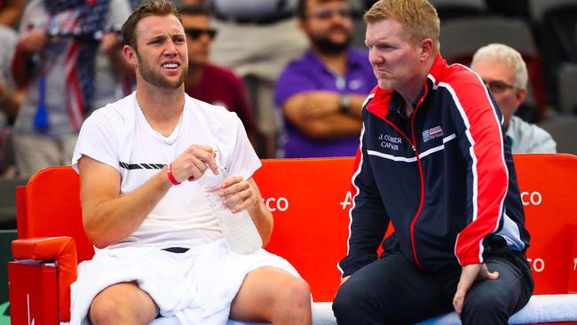 US team Captain Jim Courier (R) speaks with Jack Sock after a game against Australia's Jordan Thompson during the first match of the Davis Cup World Group tennis quarter-final clash