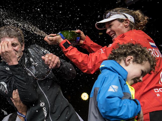 Dutch trimmer Carolijn Brouwer, with her son Kyle, sprays champagne on French skipper Charles Caudrelier as they celebrate winning the Volvo Ocean Race.