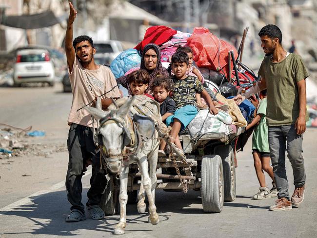 TOPSHOT - A man gestures while leading a donkey pulling a cart transporting his family members and belongings as they try to return to their home in the Tuffah district east of Gaza City on July 8, 2024 amid the ongoing conflict in the Palestinian territory between Israel and Hamas. (Photo by Omar AL-QATTAA / AFP)