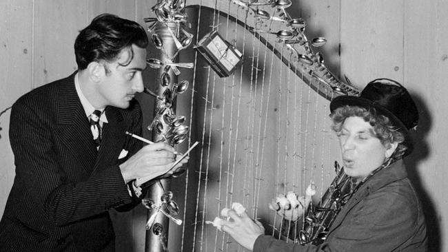 Artist Salvador Dali with comedian Harpo Marx after giving him the Christmas gift of an artwork of a harp with barbed wire strings. Circa 1936-37 Out of copyright