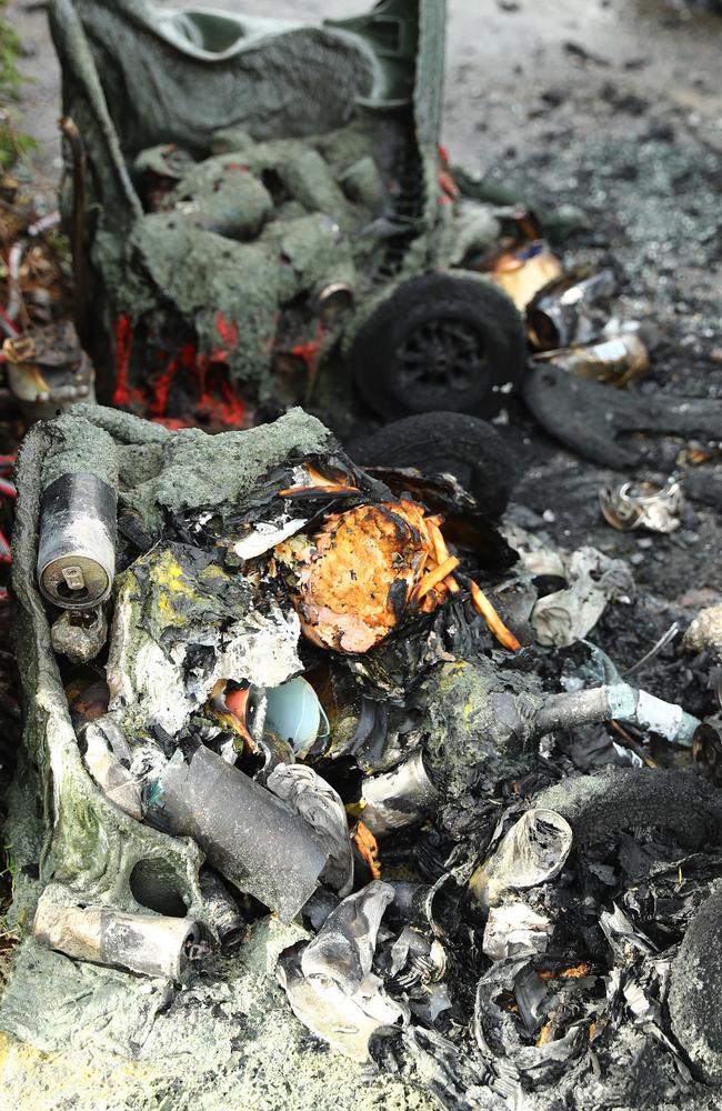 The destroyed rubbish bins beside a car torched in the driveway of a Reigate Rd Highton property. Picture: Alison Wynd