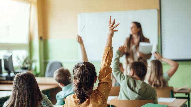 Students raising hands while teacher asking them questions in classroom