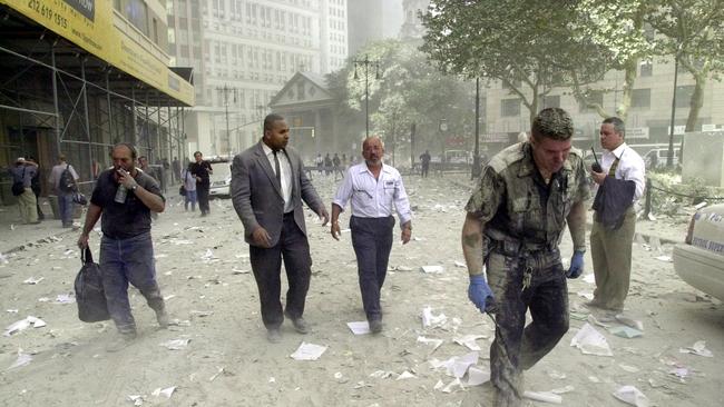 A police officer and office workers walk in streets covered in debris following the collapse of the twin towers of the World Trade Centre.