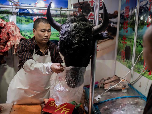 A butcher sells a yak's head to a customer at a market in Beijing.