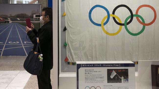 A man wearing a face mask takes pictures of the mascots for the Tokyo 2020 Olympics and Paralympics. Picture: AP