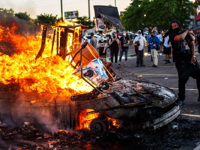 Protesters throw objects into a fire. Picture: AFP