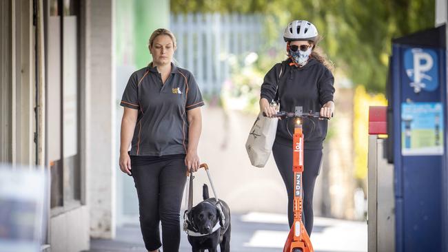 An e scooter passes guide dog trainer Rachael Hackney and Jonty at Hobart. Picture: Chris Kidd