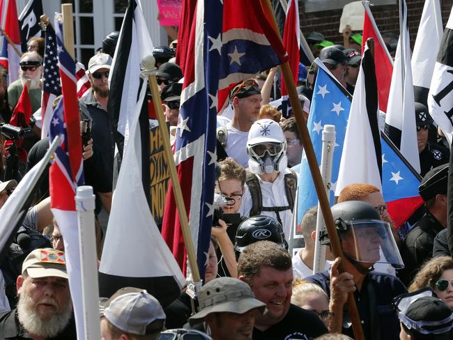 White nationalist demonstrators walk into the entrance of Lee Park surrounded by counter demonstrators in Charlottesville, Va. People were using social media to identify and shame white nationalists who attended. Picture: Steve Helber