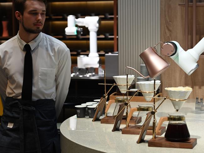 A man dressed in a barrista's outfit watches as an LG CLOi CoBot Barista robot makes pour-over coffee, at the LG booth, January 8, 2020 at the 2020 Consumer Electronics Show (CES) in Las Vegas, Nevada. - CES is one of the largest tech shows on the planet, showcasing more than 4,500 exhibiting companies representing the entire consumer technology ecosystem. (Photo by Robyn Beck / AFP)