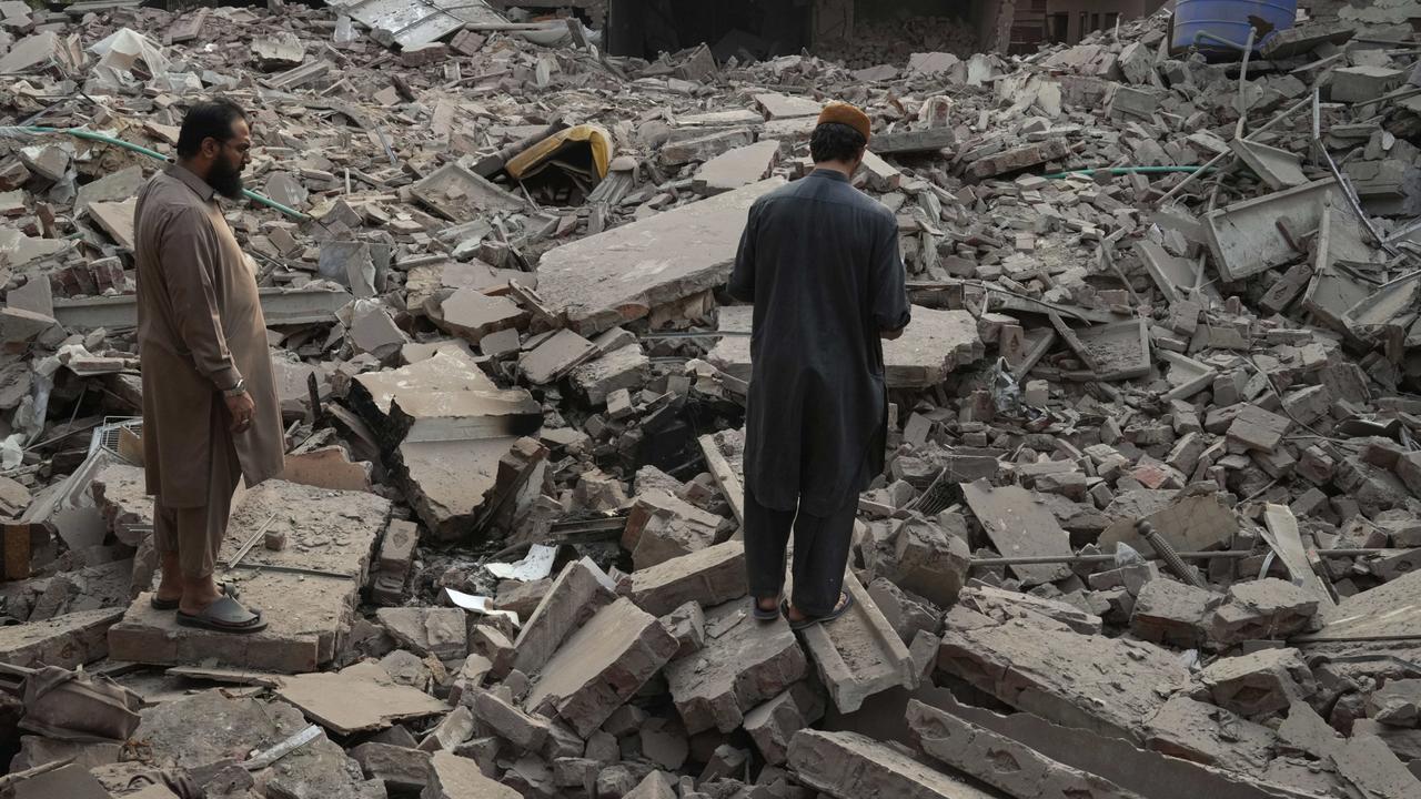 Locals stand amid the rubble of a building destroyed by India’s strikes. Picture: K.M. Chaudary/AP