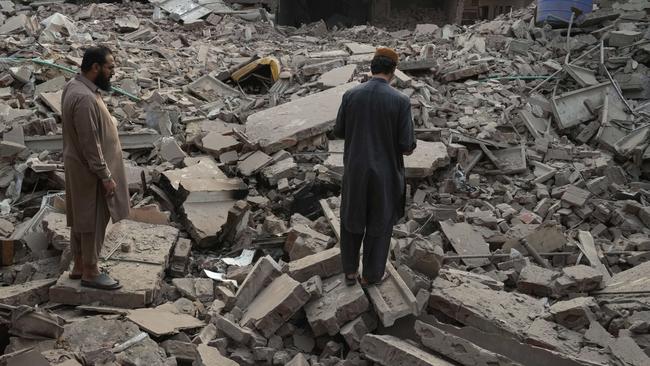 Locals stand amid the rubble of a building destroyed by India’s strikes. Picture: K.M. Chaudary/AP