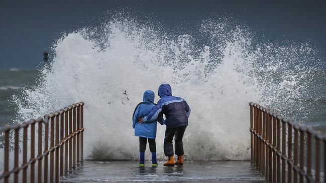 Maeva and her son Rennie get drenched by waves on a pier at Middle Park. Picture: David Caird